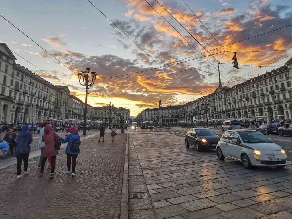 Cars and people on the city center of Turin, Italy during sunset.